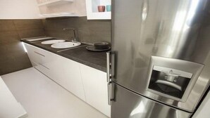 Una cocina moderna con electrodomésticos de acero inoxidable, armarios blancos y un dispensador de agua integrado.