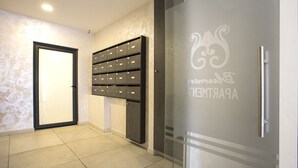 Un pasillo con una puerta, un archivador fijado a la pared y una puerta de vidrio esmerilado con un logotipo.