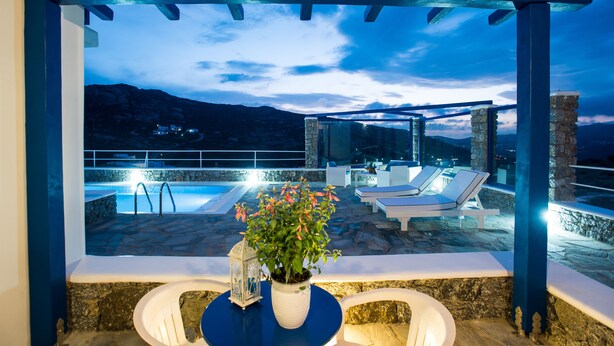 A rooftop pool area with lounge chairs and a potted plant.