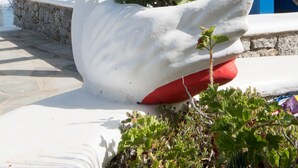 A large white swan sculpture with red flowers, blue wooden beams, and a white building with blue trim in the background.