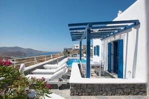 A white building with a pool and blue doors, overlooking a coastal landscape. - Mykonos Pro-care Suites (Mykonos)
