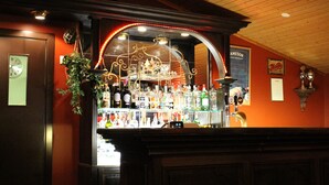 Un espace bar avec une variété de bouteilles d’alcool, une horloge au mur et une arche décorative.