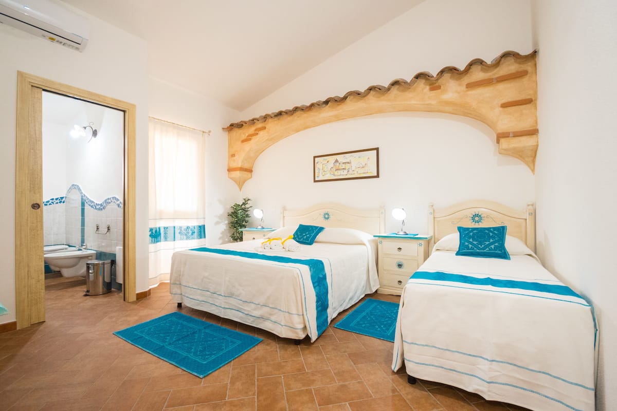 A bedroom with two beds, a bathroom, and a tiled floor.