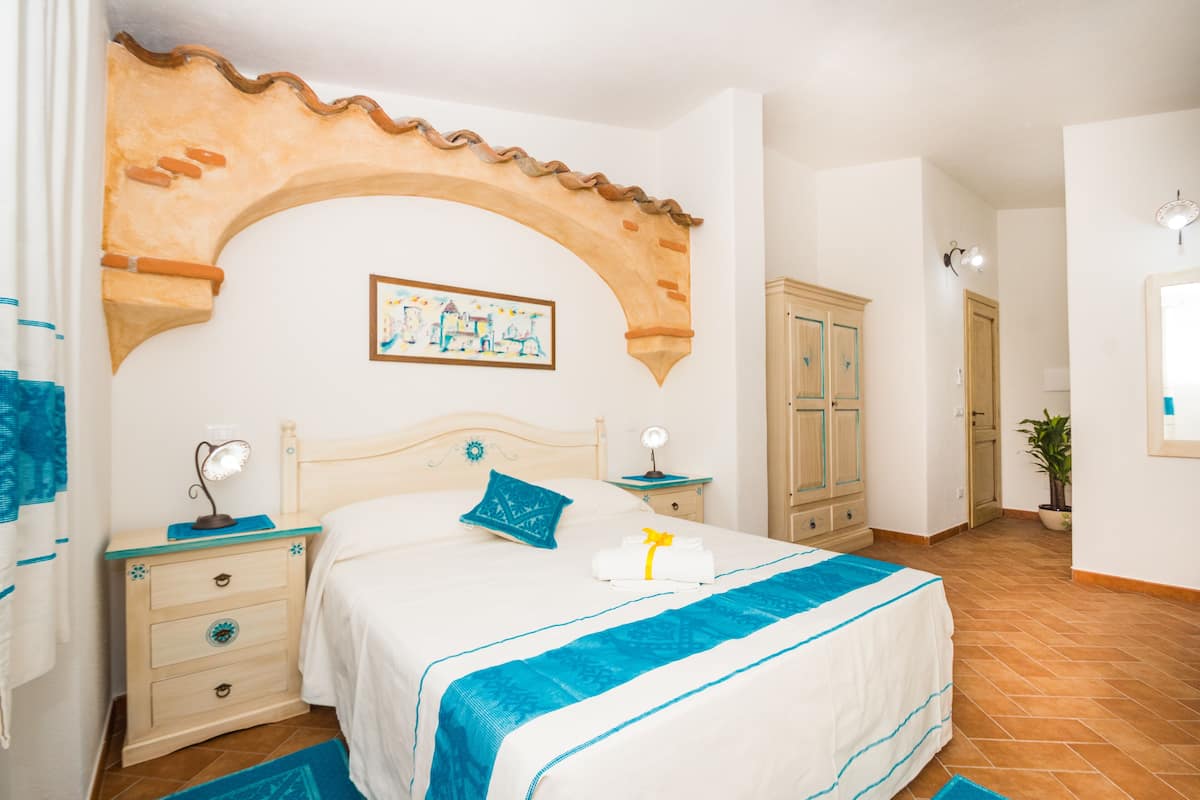 A bedroom with a bed, nightstands, a wardrobe, and a decorative archway.