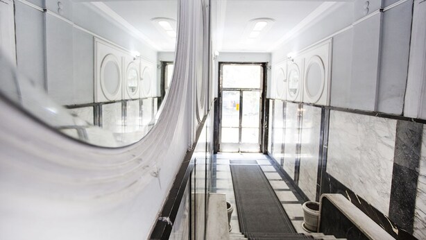 A marble-floored hallway with a central spiral staircase, leading to a door at the end. - Apartment Tiffany (Belgrade)