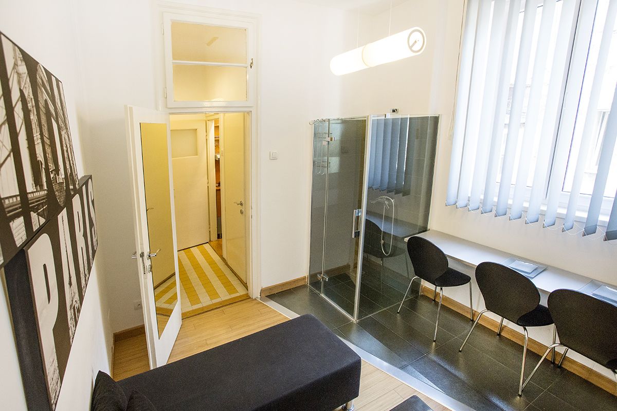 A modern bathroom with a glass shower enclosure, a bench, and a seating area with chairs.