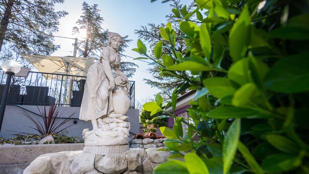 A stone statue in a garden setting with a stone base and steps. - Hotel Villa Sandi (Cavle)