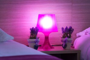 A bed with a pink lamp, two potted plants, and a wooden wall. - Hotel Villa Sandi (Cavle)
