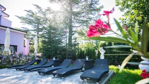 A poolside area with lounge chairs and a statue. - Hotel Villa Sandi (Cavle)