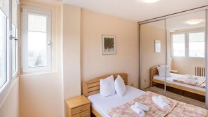 A bedroom with a single bed, a bedside table, a mirror, and a window. - Apartment Loti (Belgrade)