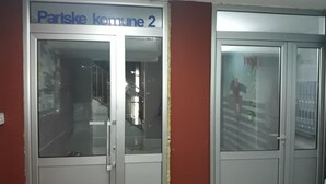 A door with a sign reading "Pariske kommune 2" and a glass panel reflecting a staircase. - Apartment Loti (Belgrade)