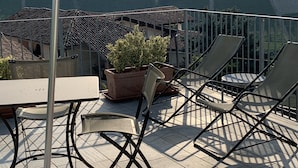 A terrace with a table, chairs, and a potted plant. - Residence delle Rose (Monforte d'Alba)