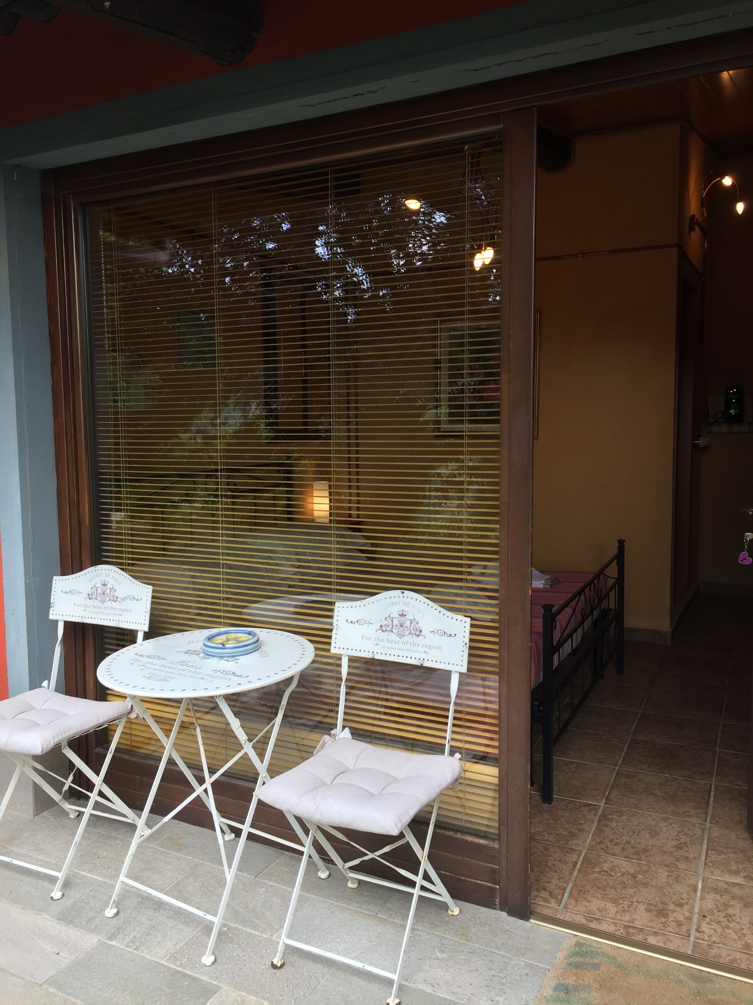 Een terras met een tafel, stoelen, een bed en een decoratieve muur.