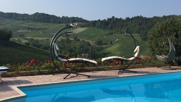 A swimming pool with a view of rolling hills and a decorative metal sculpture. - Residence delle Rose (Monforte d'Alba)