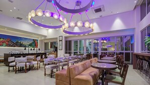 Un restaurante moderno con una zona de estar central, un bar y un mural en la pared.
