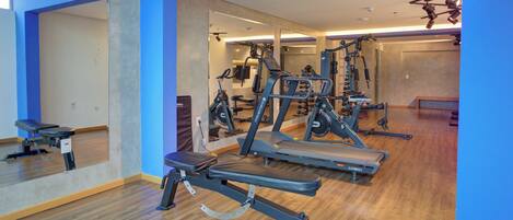 A gym with exercise equipment, wooden floors, and blue walls.