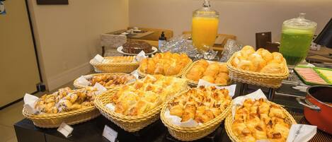 Un bufé con diversas opciones de panadería y bebidas.