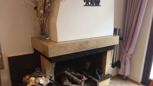 A fireplace with logs, a vase with flowers, and a decorative plate on the mantel. - Hotel Garni Fuchs (Eichstaett)