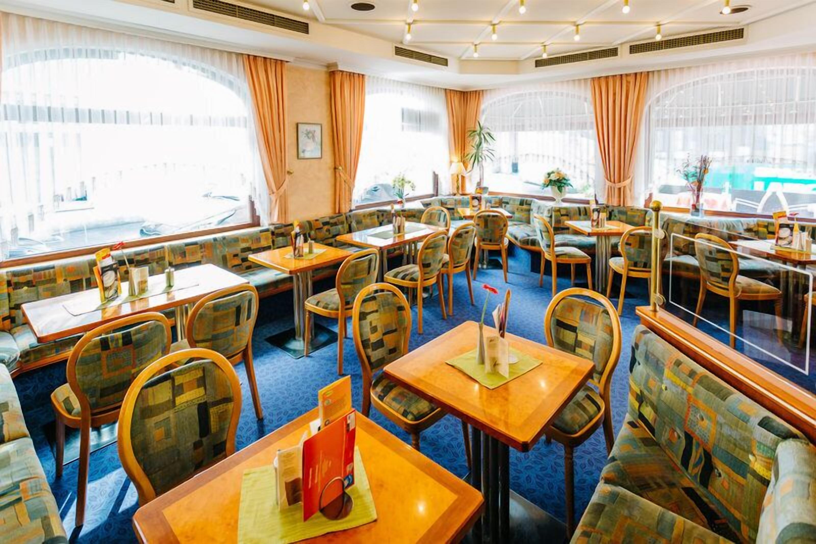 A restaurant with multiple seating areas, including booths and tables, with large windows providing views of the outside.