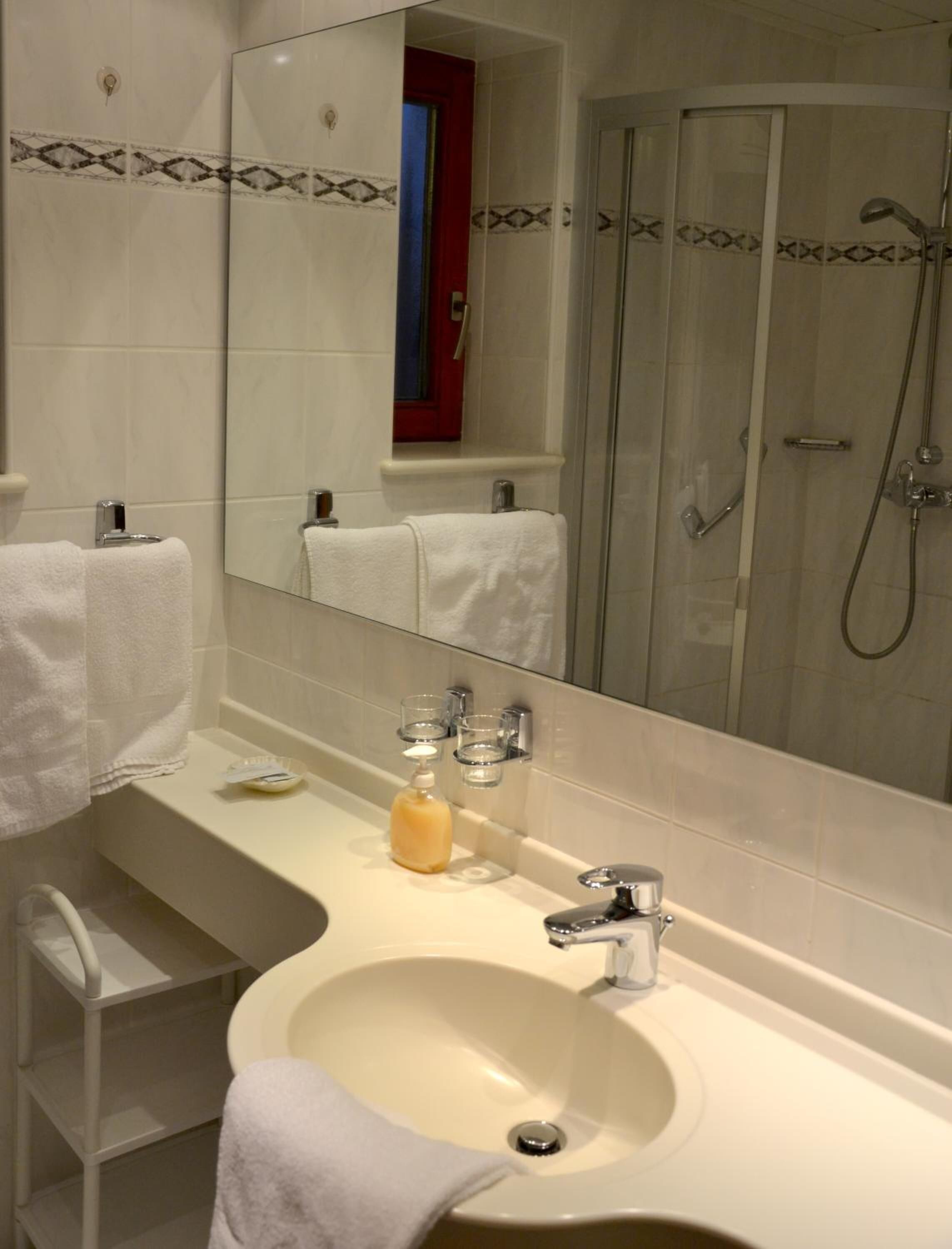 Ein Badezimmer mit Waschbecken, Spiegel und Dusche.
