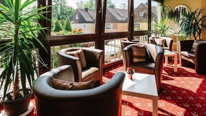 A sunlit room with leather chairs, a small table, and potted plants. - Hotel Garni Fuchs (Eichstaett)