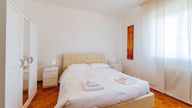 A neatly arranged bedroom with a bed, bedside tables, a wardrobe, and a painting on the wall. - Welc-oM Manuela (Selvazzano Dentro)