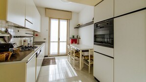 A compact kitchen with white cabinets, a gas stove, and a built-in oven. - Welc-oM Manuela (Selvazzano Dentro)