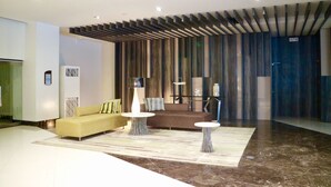 A modern lobby with a sofa, two tables, and a patterned rug. - Eastwood Le Grand Tower 3 (Quezon City)