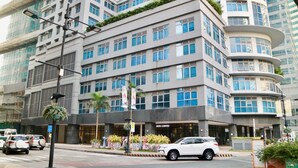 A multi-story hotel with a modern design, featuring a curved corner facade, large windows, and a visible coffee shop on the ground floor. - Eastwood Le Grand Tower 3 (Quezon City)