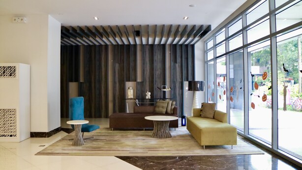 A modern lobby with a large window, a brown sofa, a yellow sofa, and a blue chair. - Eastwood Le Grand Tower 3 (Quezon City)