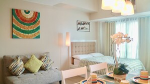 A modern bedroom with a sofa, a bed, a dining table, and a decorative plant. - Eastwood Le Grand Tower 3 (Quezon City)