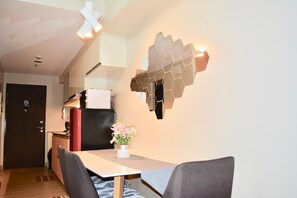Een moderne keuken met een eettafel, stoelen en een decoratief wandobject.
