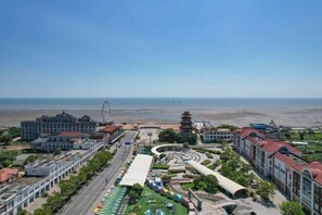 A coastal cityscape with a prominent building, a pagoda, and a road leading to the beach. - Rihai Hotel Shanghai (Shanghai)
