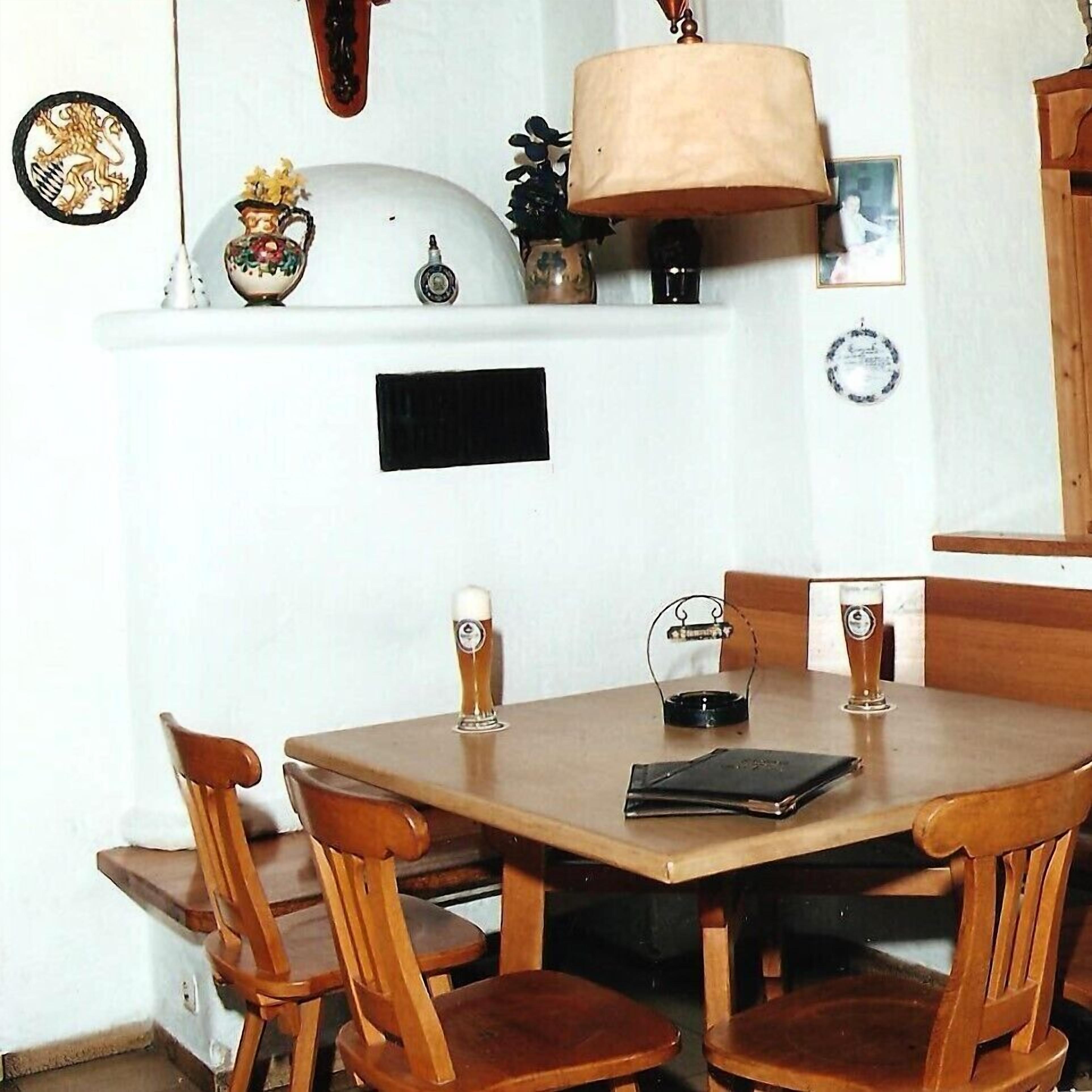 A dining area with a wooden table and chairs, a lamp, and a decorative plate on the wall.