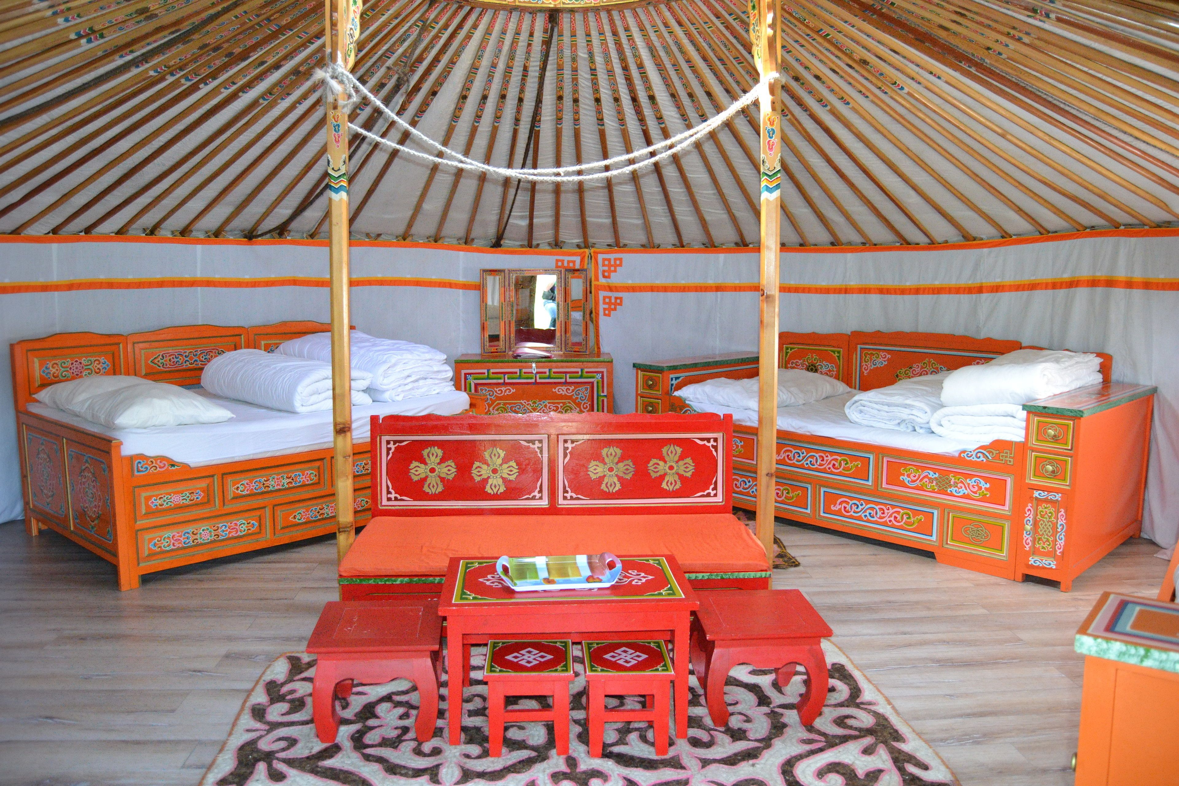 A traditional yurt with two beds, a central table, and matching chairs.