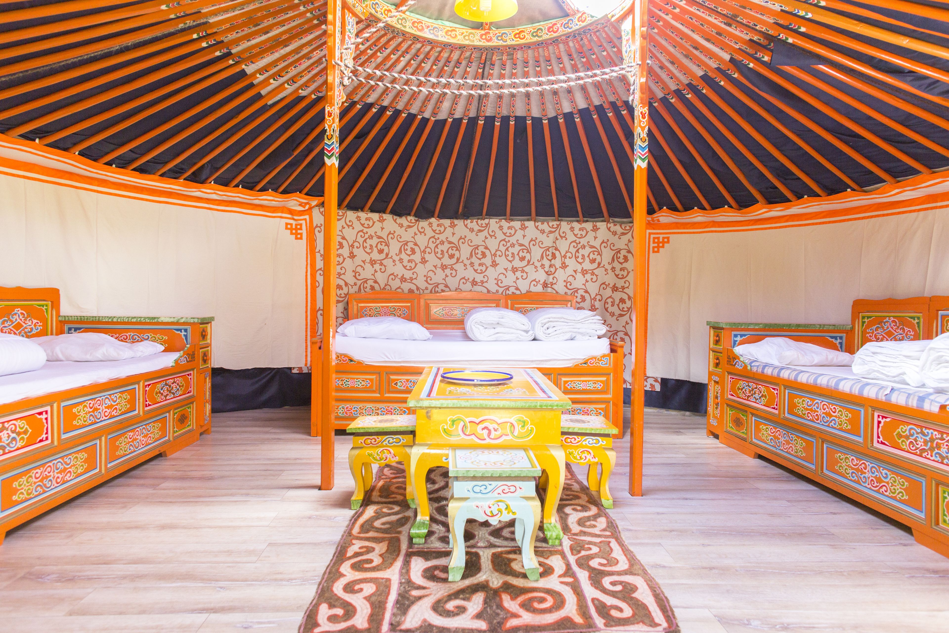 A traditional tent-style room with a central bed, two smaller beds, and a table with chairs.