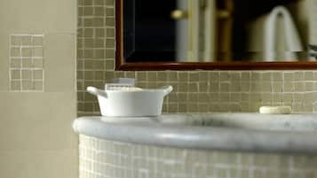 Une salle de bain avec un mur recouvert de carreaux derrière le lavabo, un lavabo blanc et un miroir au-dessus.