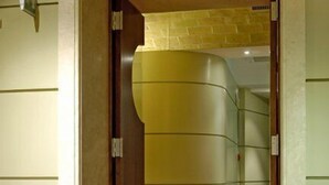 Una escalera de madera conduce a una habitación con una pared curva y una lámpara a la izquierda.