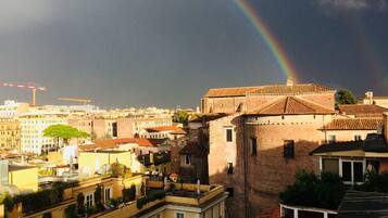A cityscape with a prominent building featuring a red-tiled roof and a visible rainbow.