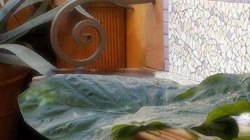 A tiled wall with a mosaic pattern, a metal spiral decoration, and potted plants.