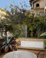 A patio with a mosaic-tiled bench, potted plants, and a lattice fence.