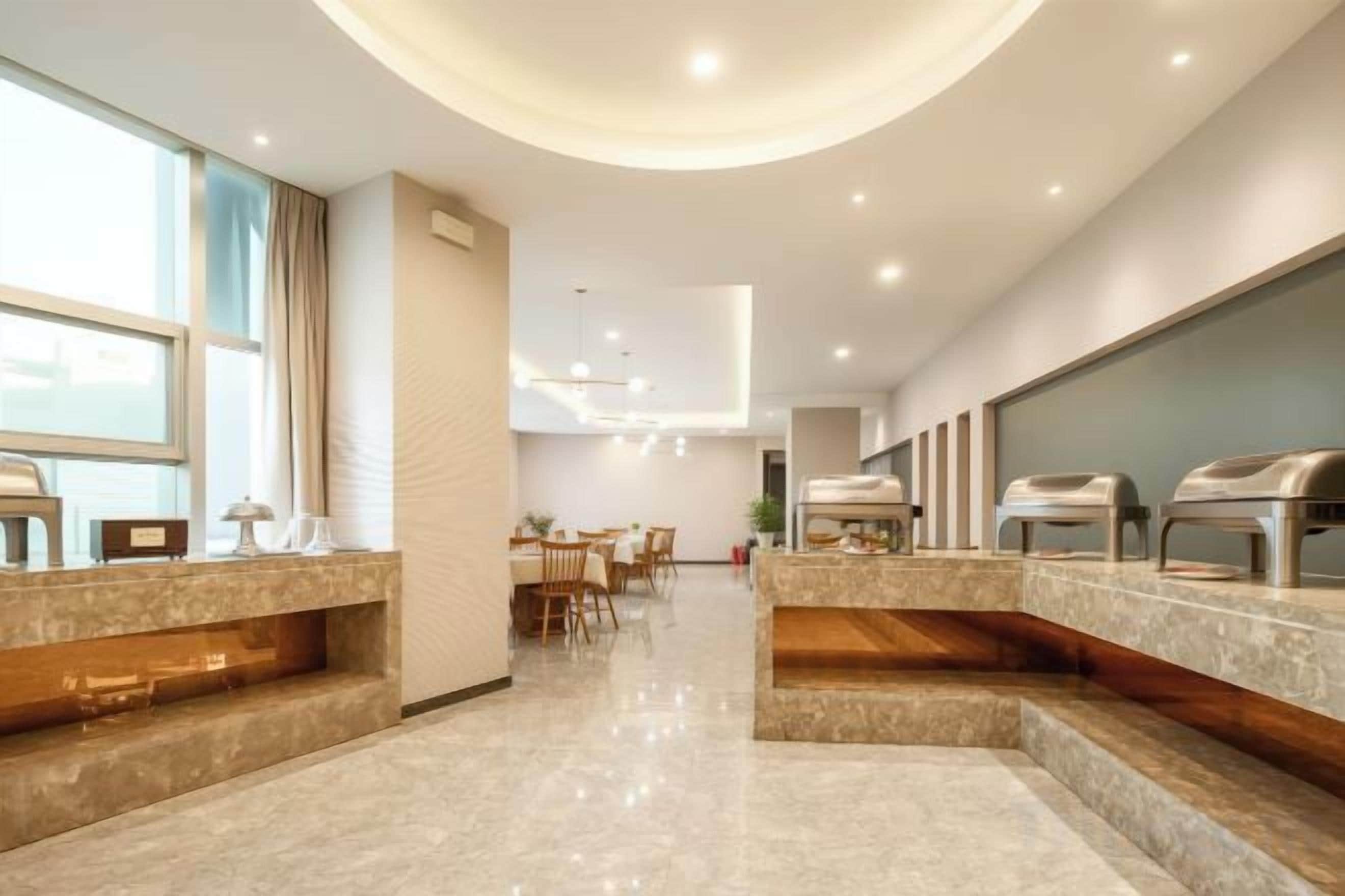 A modern hotel lobby with a reception desk, seating area, and buffet.