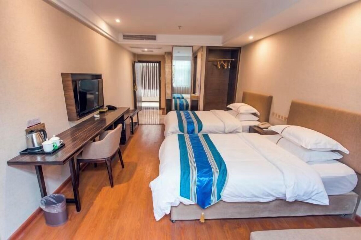 A hotel room with a bed, a desk, a television, and a view of the outside.