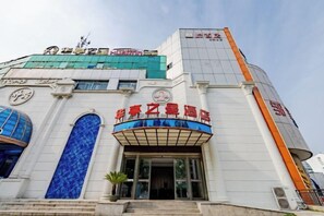A hotel with a prominent entrance, large windows, and a sign with Chinese characters. - Huating Business Hotel (Tongling)