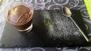 Ein Dessert mit Schokoladenmousse, einem Minzblatt und Puderzucker auf einem Schieferpräsentierteller.
