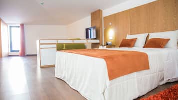 A modern hotel room with a large bed, a desk, and a television.