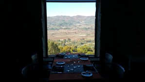 A table set for dining with a view of a hilly landscape through a window. - Belmonte Sinai Hotel (Belmonte)
