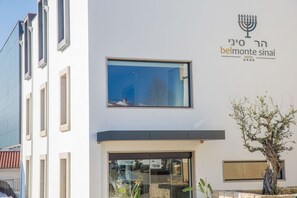 Experience the Belmonte Sinai Hotel's sleek, modern design with a prominent glass entrance and stunning views from the upper window.