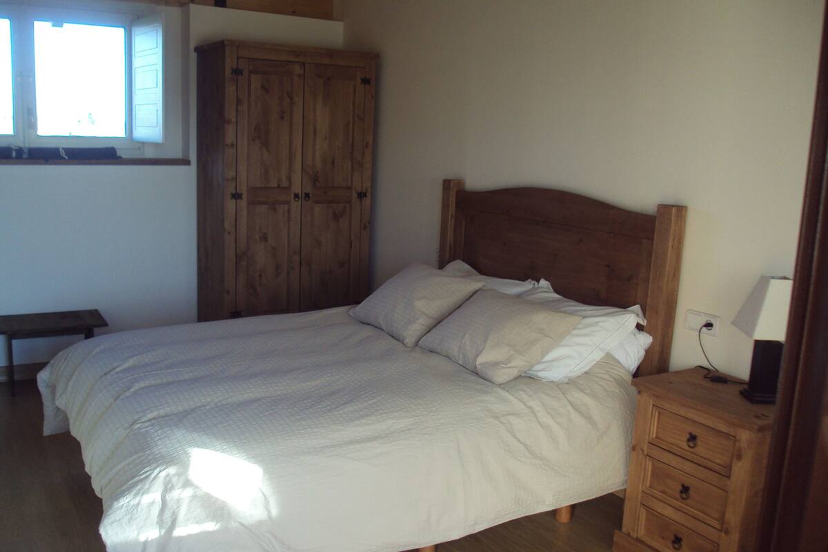 A bedroom with a wooden bed, a nightstand with a lamp, and a wardrobe.