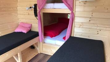 A wooden cabin with two bunk beds, each with a mattress and pillows.